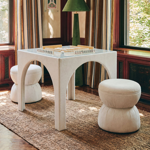 Beige ruched upholstered ottoman with rounded top and stacked cushioned base