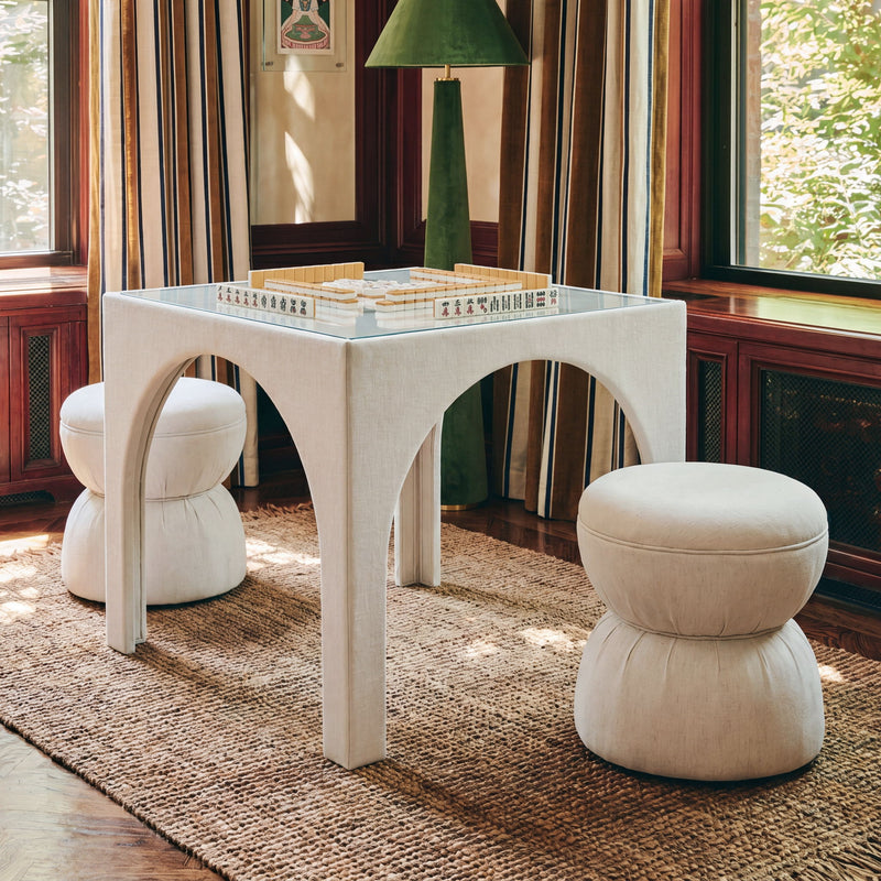 Beige ruched upholstered ottoman with rounded top and stacked cushioned base
