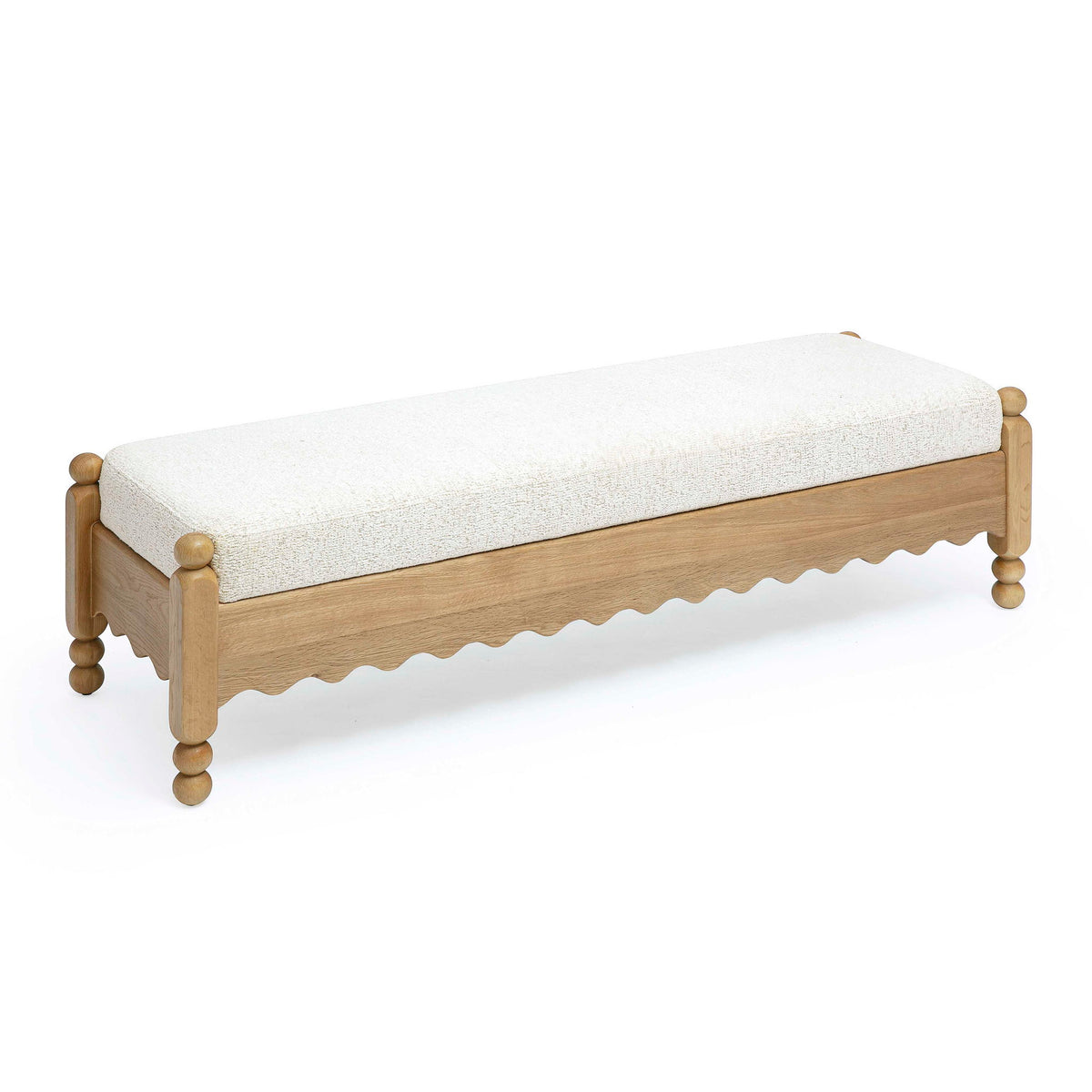 Cream upholstered bench with light wood frame and scalloped underside, four round legs.