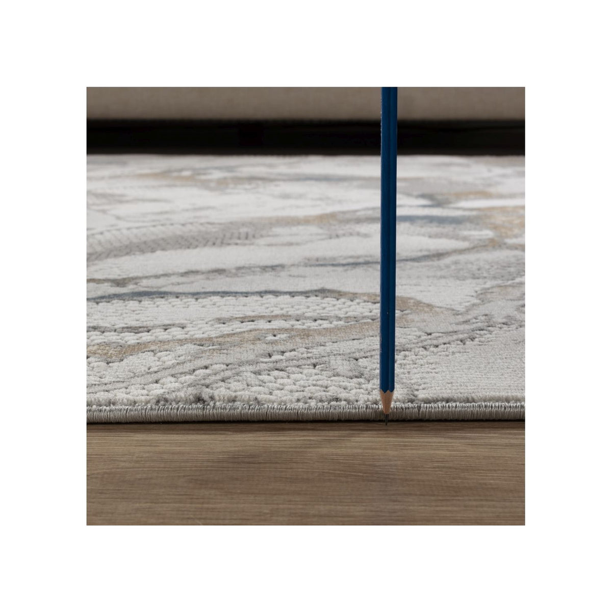 Gray rug corner with marbled pattern and textured 3D weave, edge detail
