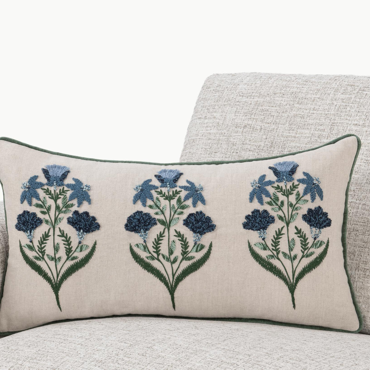 Floral lumbar pillow on sofa, natural base with blue flower sprays and green piping