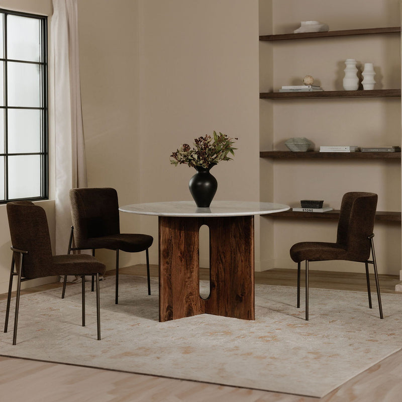 Dark brown upholstered dining chairs with slim metal legs arranged around a dining table
