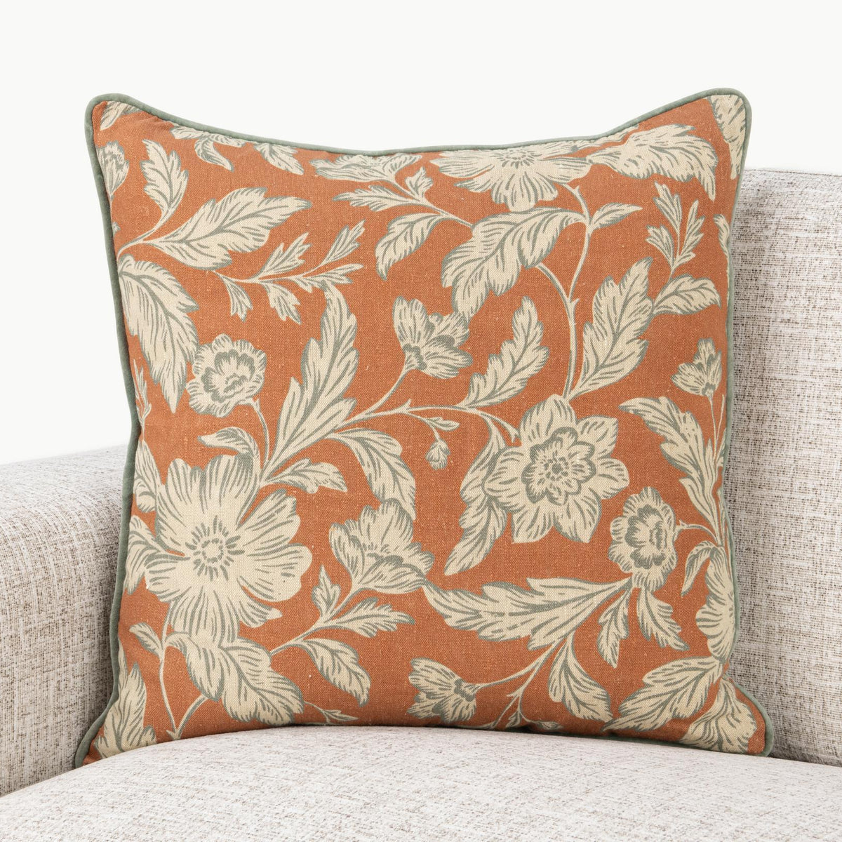 Rust floral square pillow with cream leaves and flowers and green edge piping