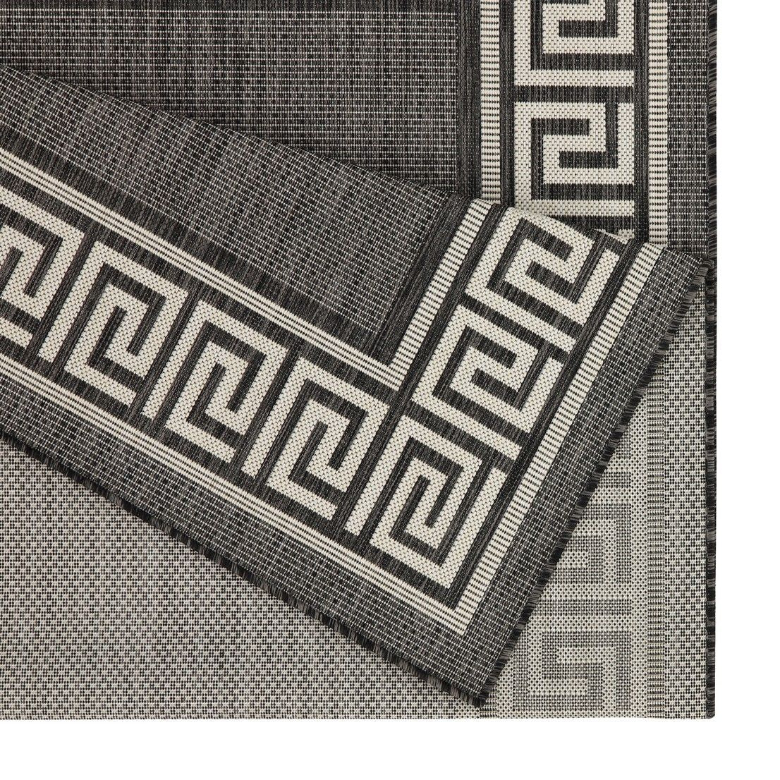 Close-up of dark gray area rug edge with Greek key border and woven texture.