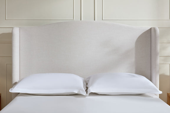Beige upholstered headboard with two pillows on a low-profile king bed