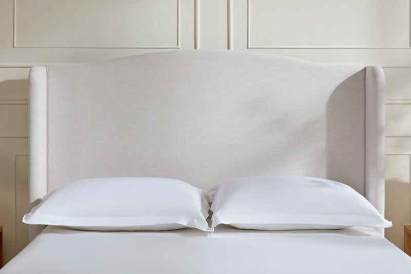 Beige upholstered headboard with two pillows on a low-profile king bed
