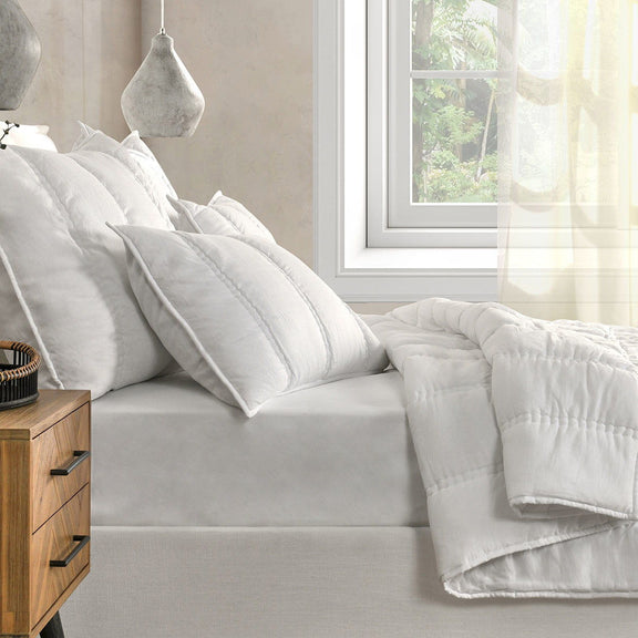 White pillow shams with vertical channel stitching on a sofa bed