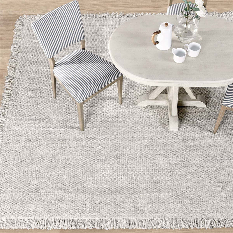 Ivory wool rug with short fringe, woven loop texture, rectangular shape.