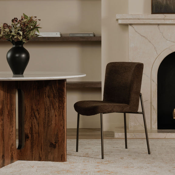 Side view of a dark brown upholstered dining chair with slim metal legs