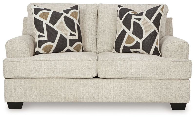 Beige loveseat with two geometric black-and-cream pillows and dark block feet
