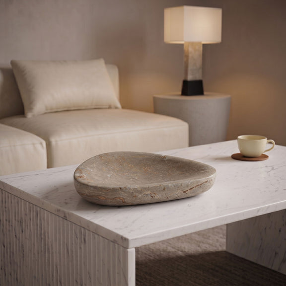 Gray travertine bowl on white table beside cup and lamp