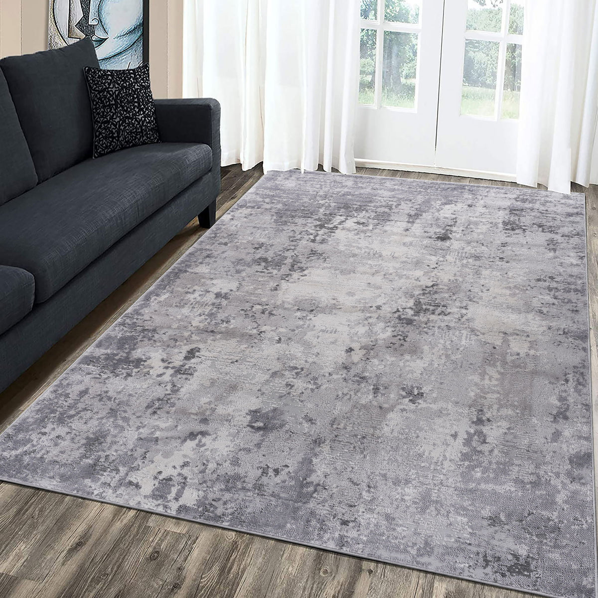 Light gray abstract area rug, rectangular, distressed pattern on wooden floor