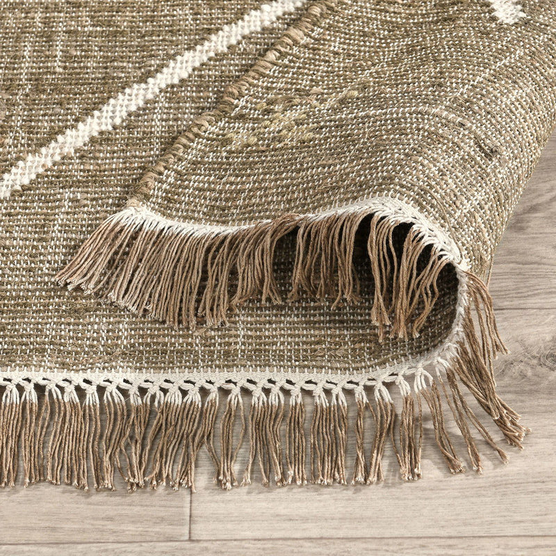 Close-up of tan woven area rug corner with fringe trim and light geometric line pattern