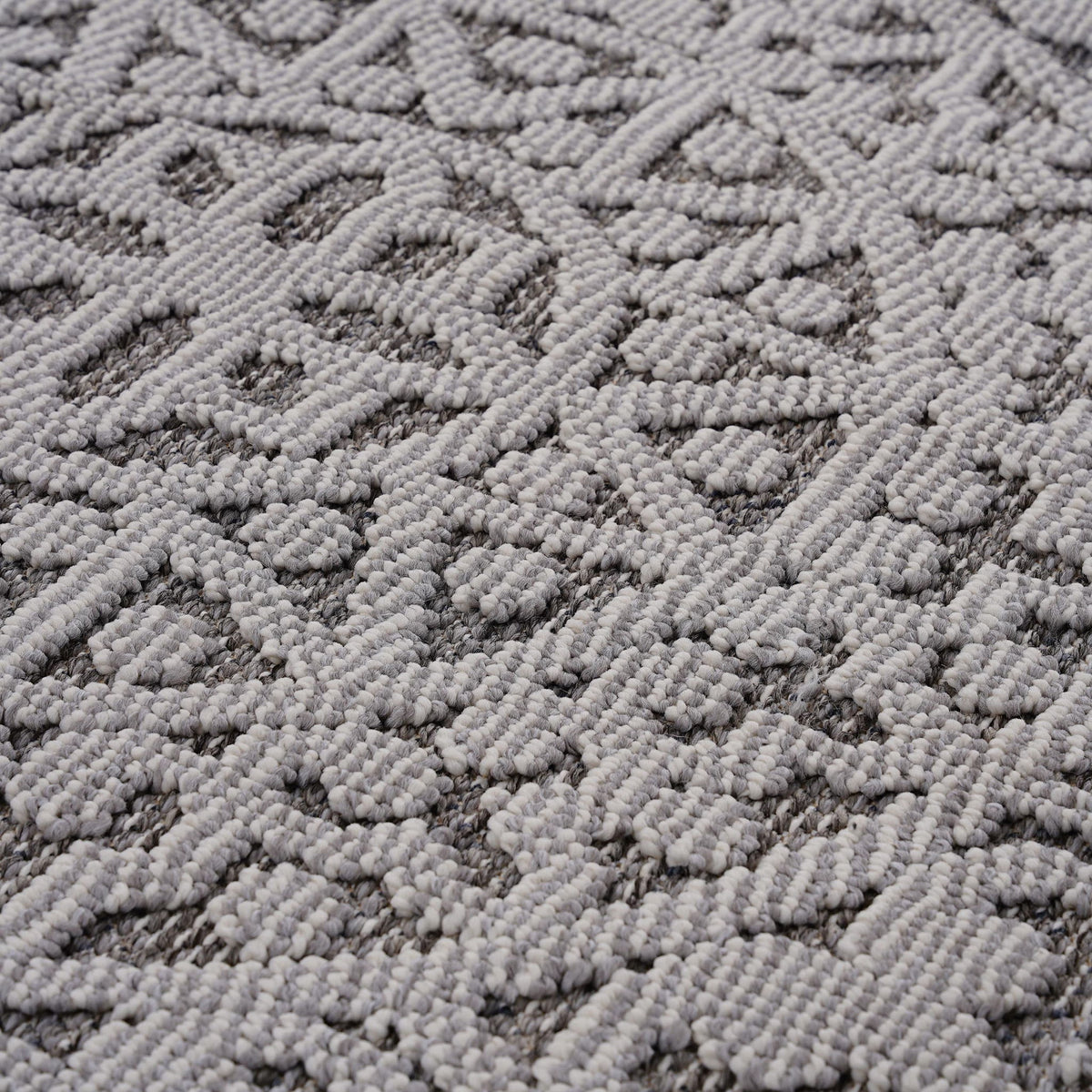 Gray and white textured rug surface with raised geometric diamond and medallion pattern