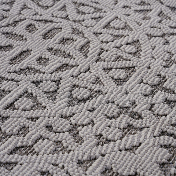 Gray and white textured rug surface with raised geometric diamond and medallion pattern