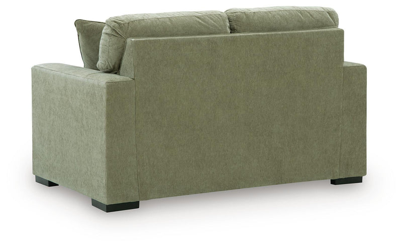 Green upholstered loveseat with square arms, tufted back cushions, and black legs