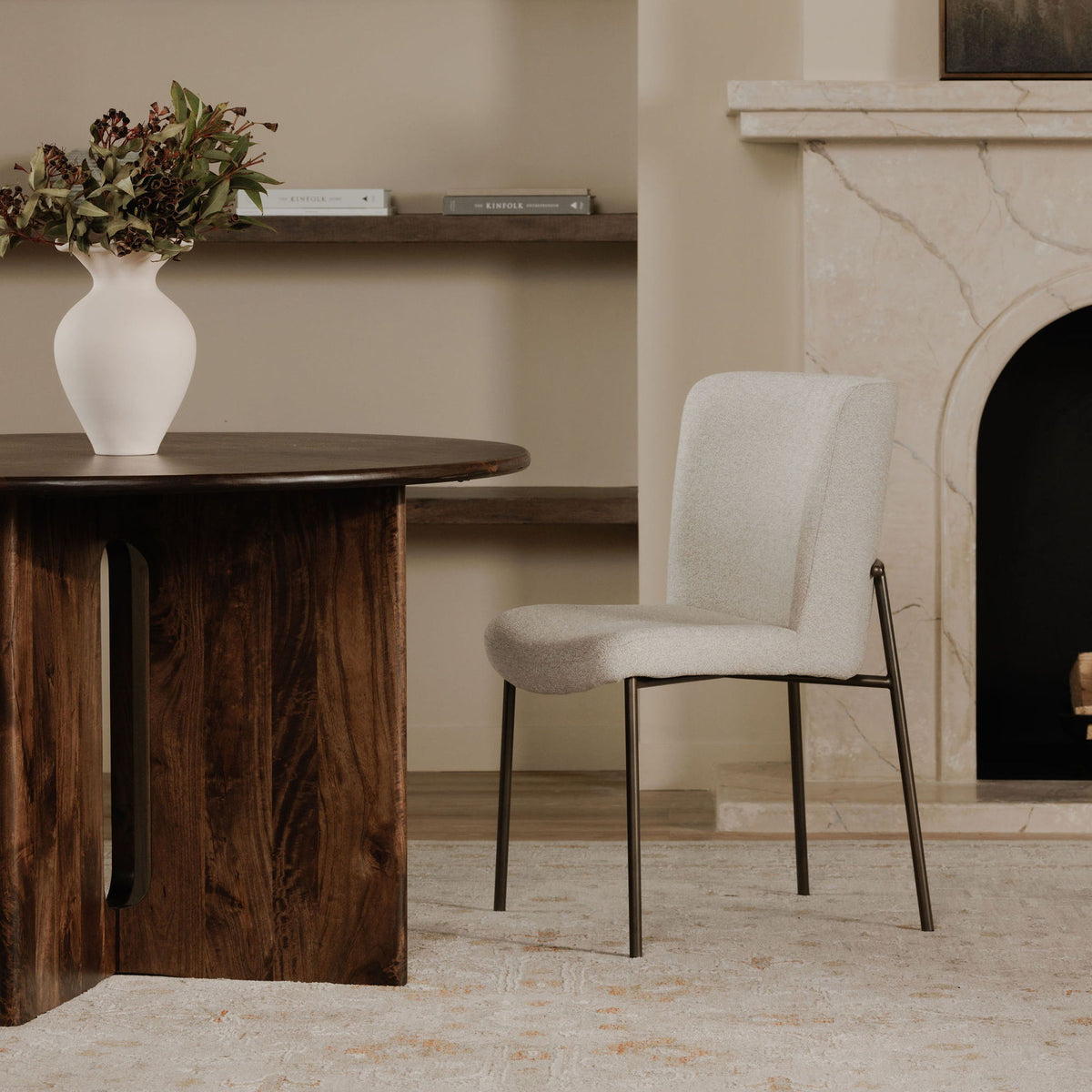 Beige upholstered dining chair shown from the side, with slim dark metal legs