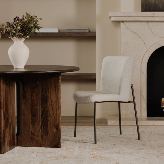 Beige upholstered dining chair shown from the side, with slim dark metal legs