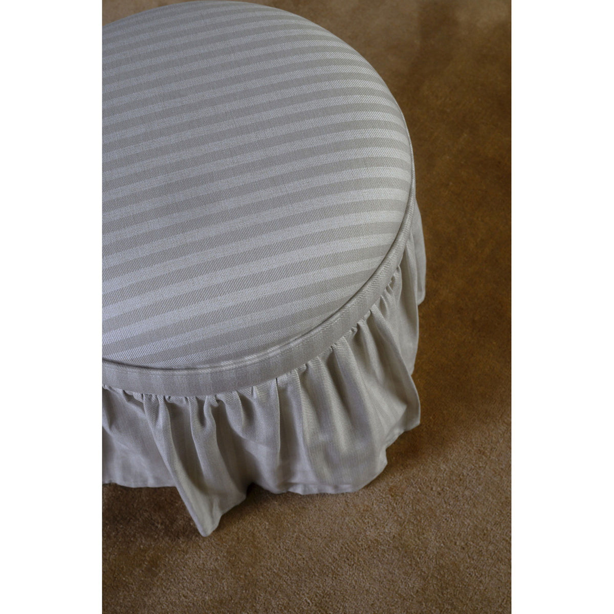 Beige striped storage ottoman close-up: round lid with pleated ruffled skirt