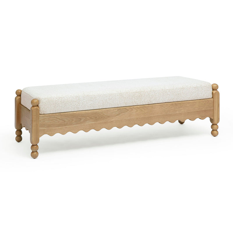 Low cream bench with textured cushion, light wood sides, scalloped apron and rounded feet.
