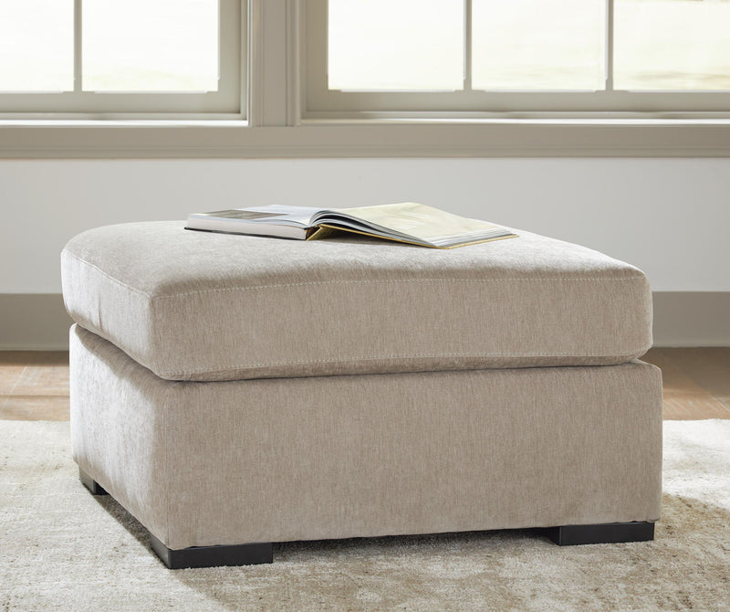 Oversized accent ottoman in light neutral fabric with black legs and open book