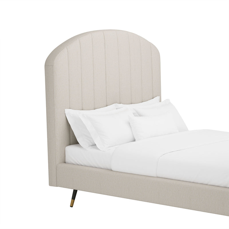 Beige arched upholstered platform bed with white pillows and duvet