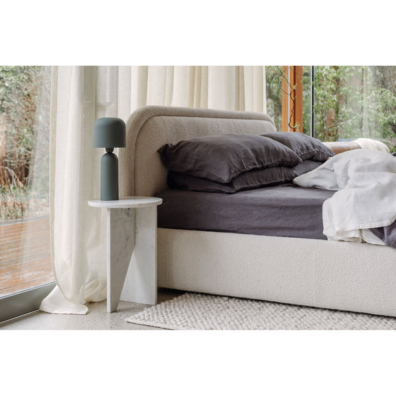 Oatmeal upholstered king bed with side panel and bedframe shown in corner view
