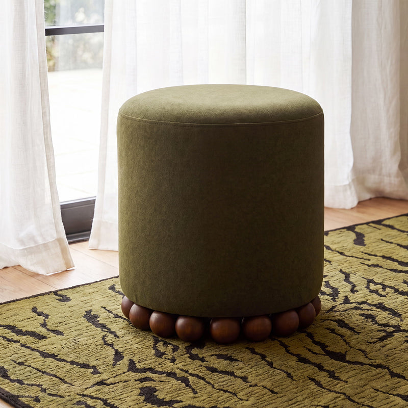 Dark green round ottoman with plush fabric and wooden ball base