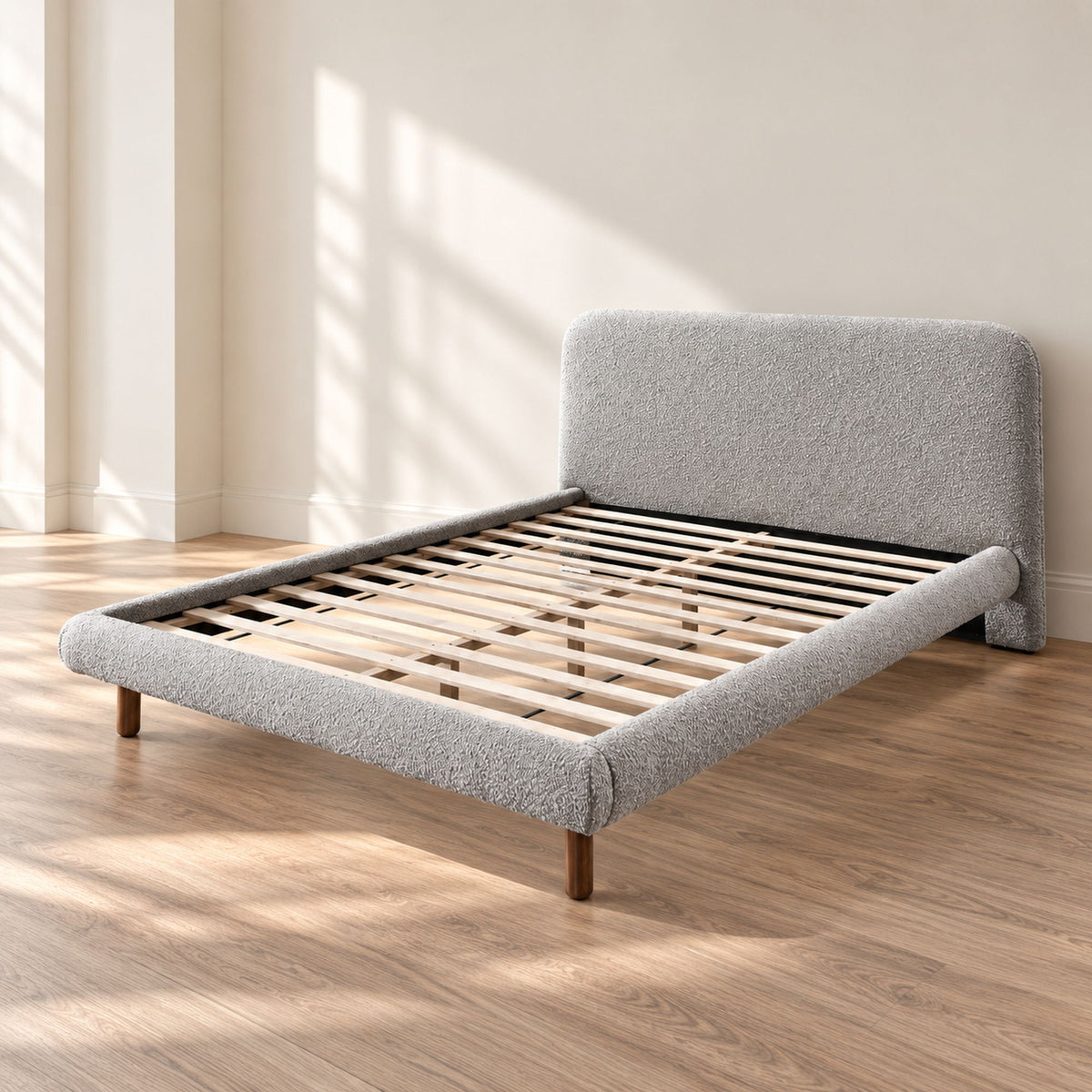 Gray upholstered platform bed with curved headboard, slatted base, and wooden legs