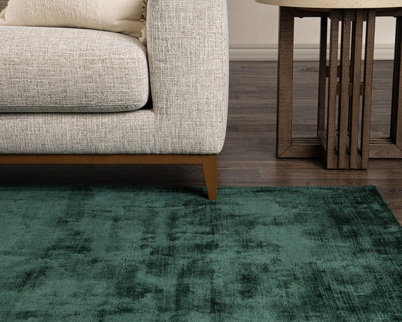 Dark green distressed area rug with clouded, vintage-style pattern and low pile.
