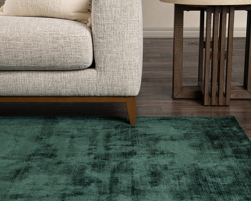 Dark green distressed area rug with clouded, vintage-style pattern and low pile.