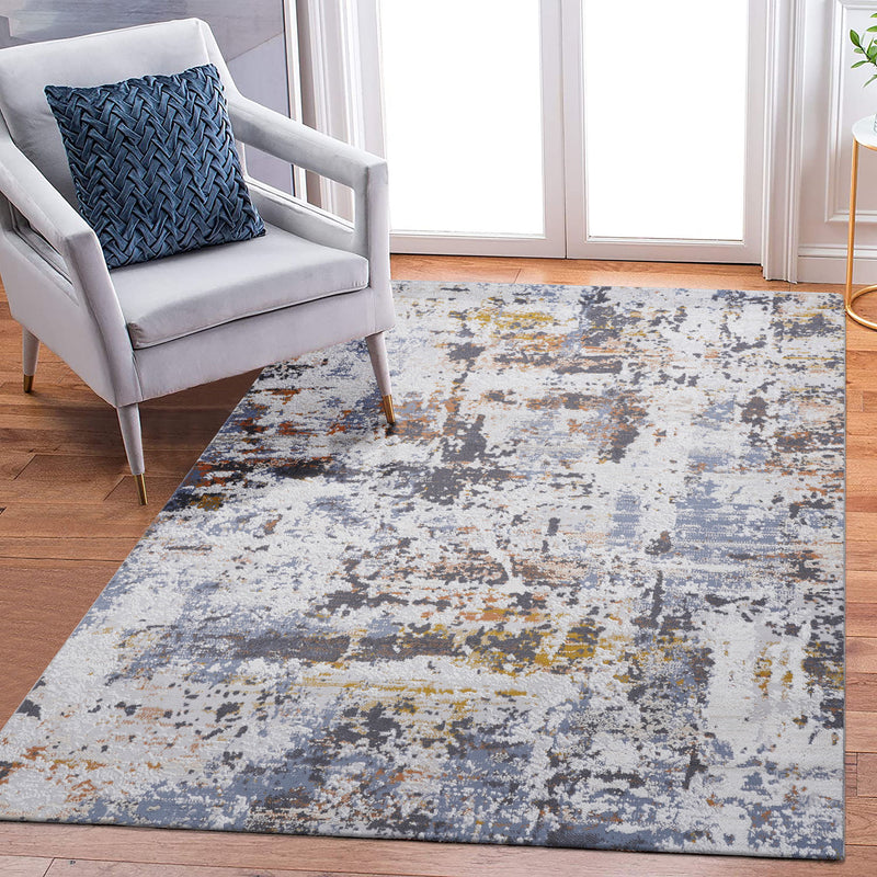 Abstract area rug with distressed blue, ivory, and gray squares and speckles