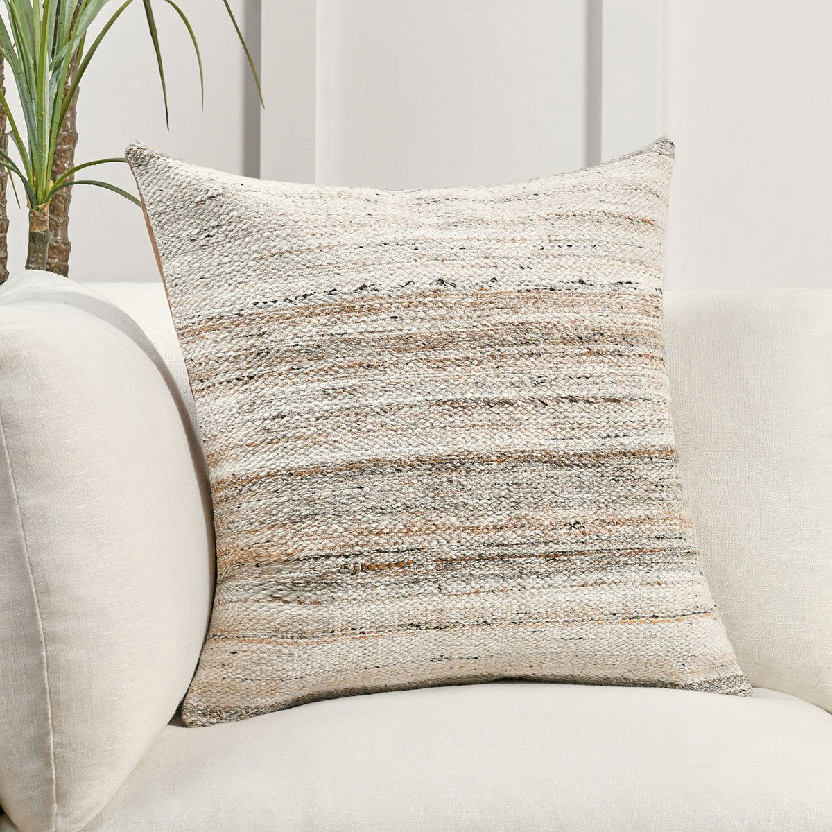 Textured sand multi striped throw pillow on a bed, square shape