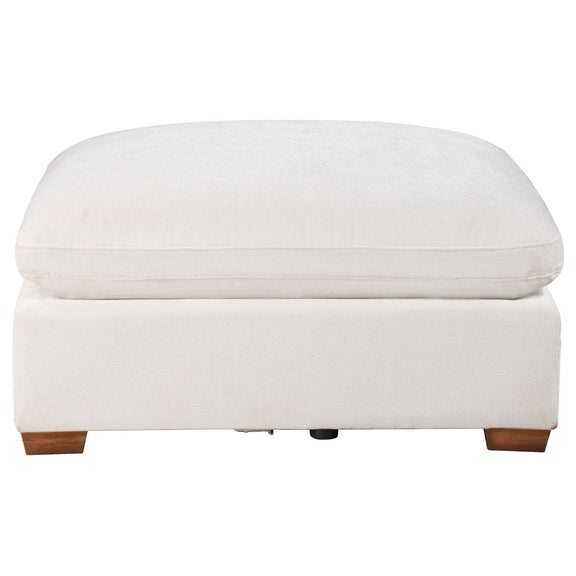White upholstered ottoman with rounded top cushion and wooden block feet.