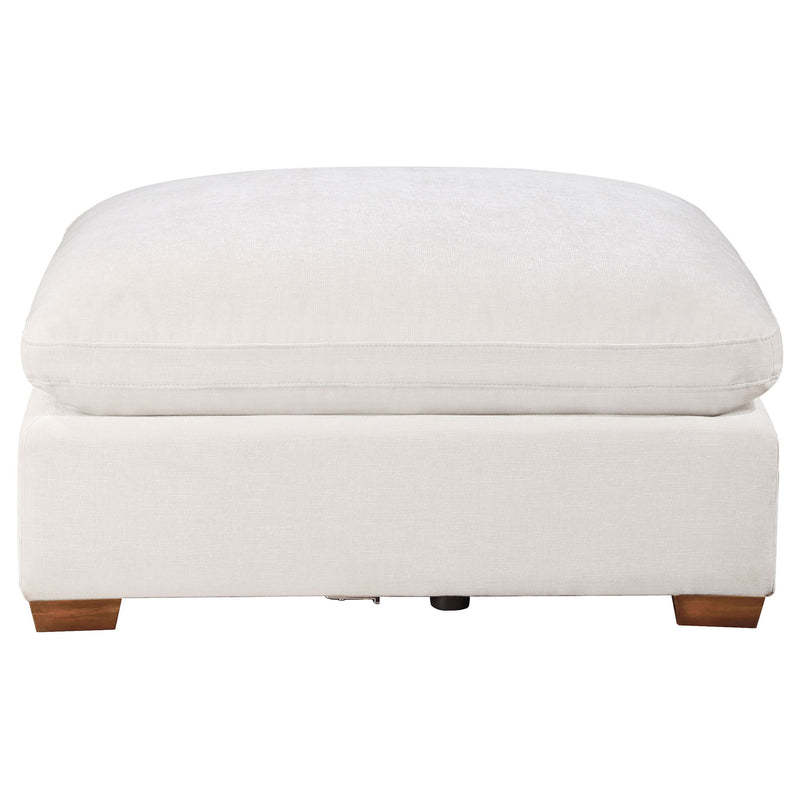 White upholstered ottoman with rounded top cushion and wooden block feet.