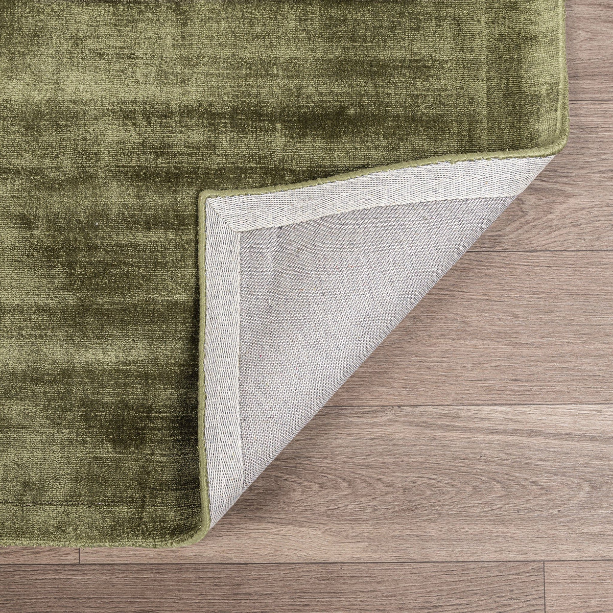 Berlin rug corner in olive green with bound edge and visible light backing