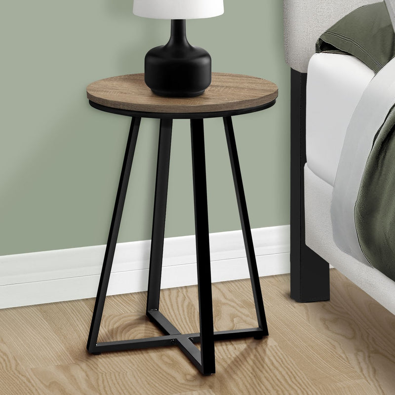 Round accent side table with light brown top and black tapered legs with cross-brace