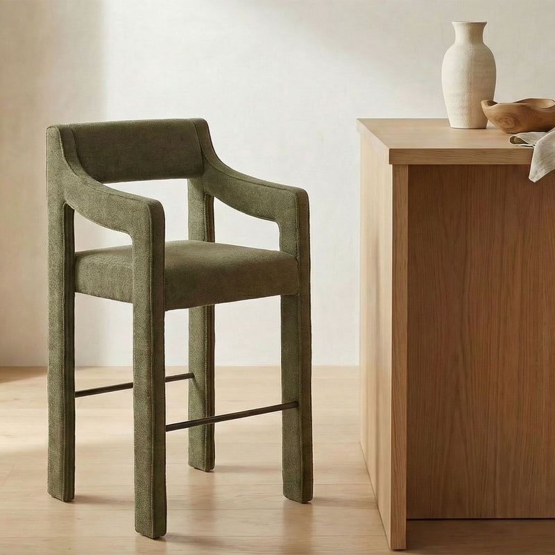 Cedar green upholstered counter stool with wide armrests, wood frame, and footrest bar