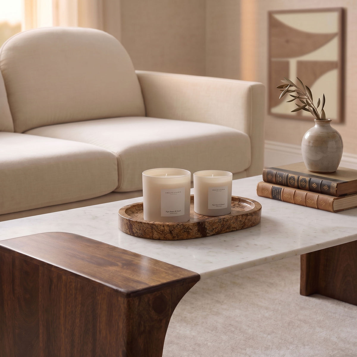 Brown marble tray holding two white candles on a table.