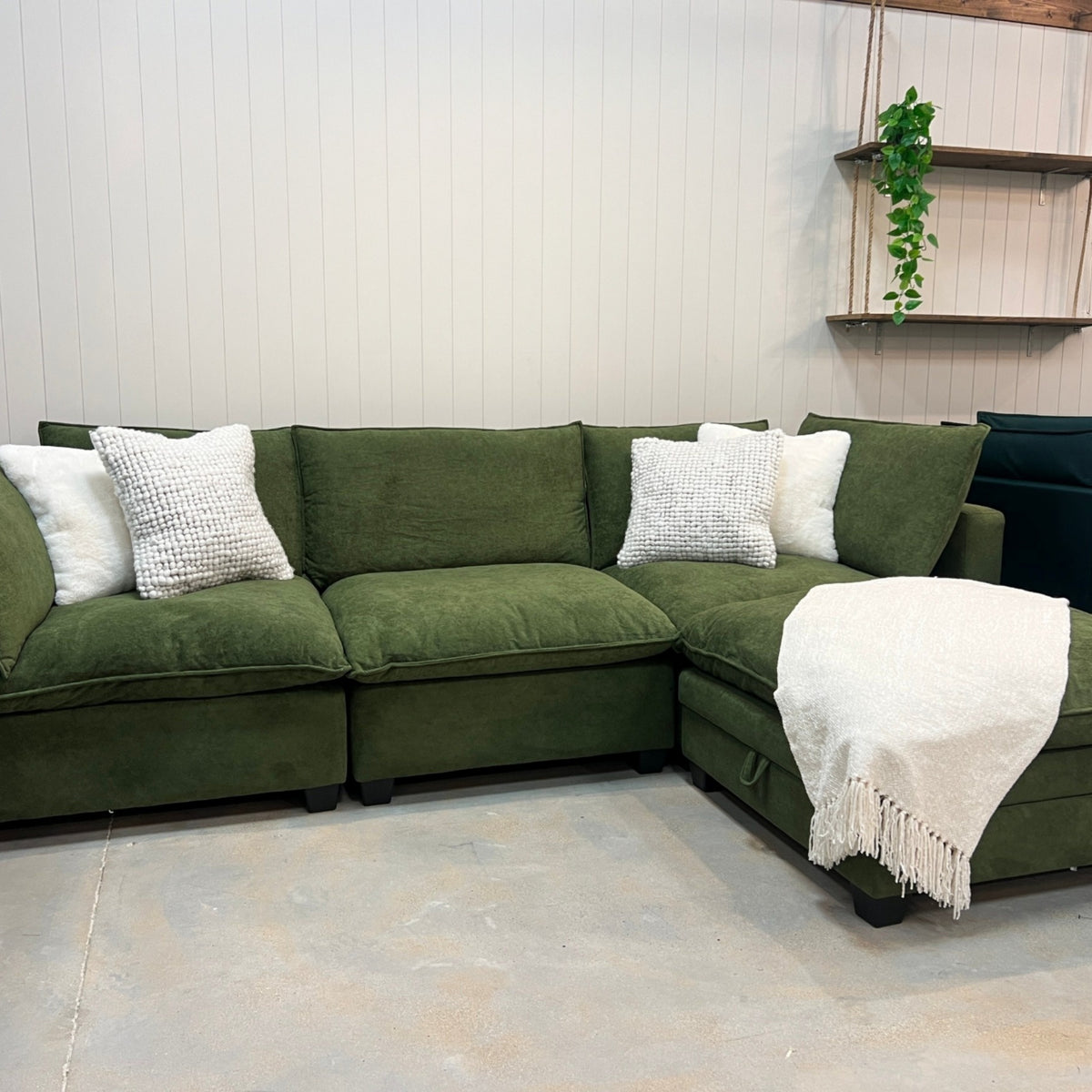 Modular sectional sofa in olive green fabric with white accent pillows and chaise