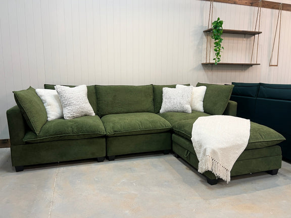 Modular sectional sofa in olive green fabric with white accent pillows and chaise