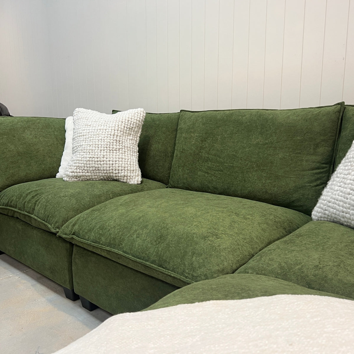 Olive green modular sectional sofa with plush cushions and textured white throw pillows