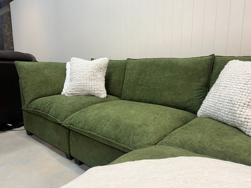 Olive green modular sectional sofa with plush cushions and textured white throw pillows
