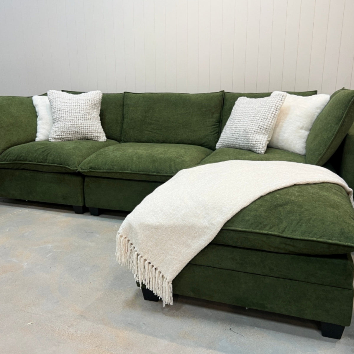 Olive green modular sectional sofa with chaise extension and white knit throw
