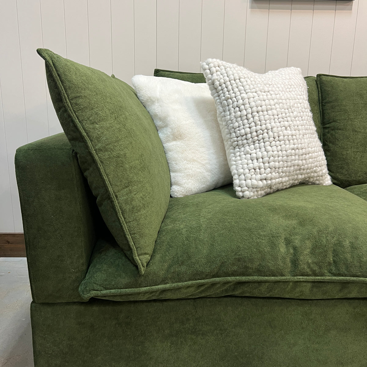Olive green modular sectional sofa with side arm and white textured throw pillows