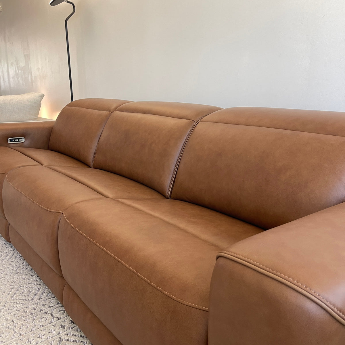 Caramel leather power reclining sectional sofa with smooth seat cushions and curved armrest