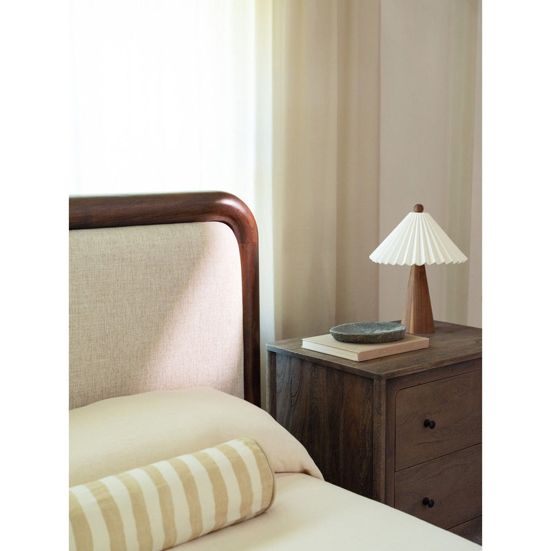 Queen bed corner with brown wood posts, beige headboard, and close-up angle