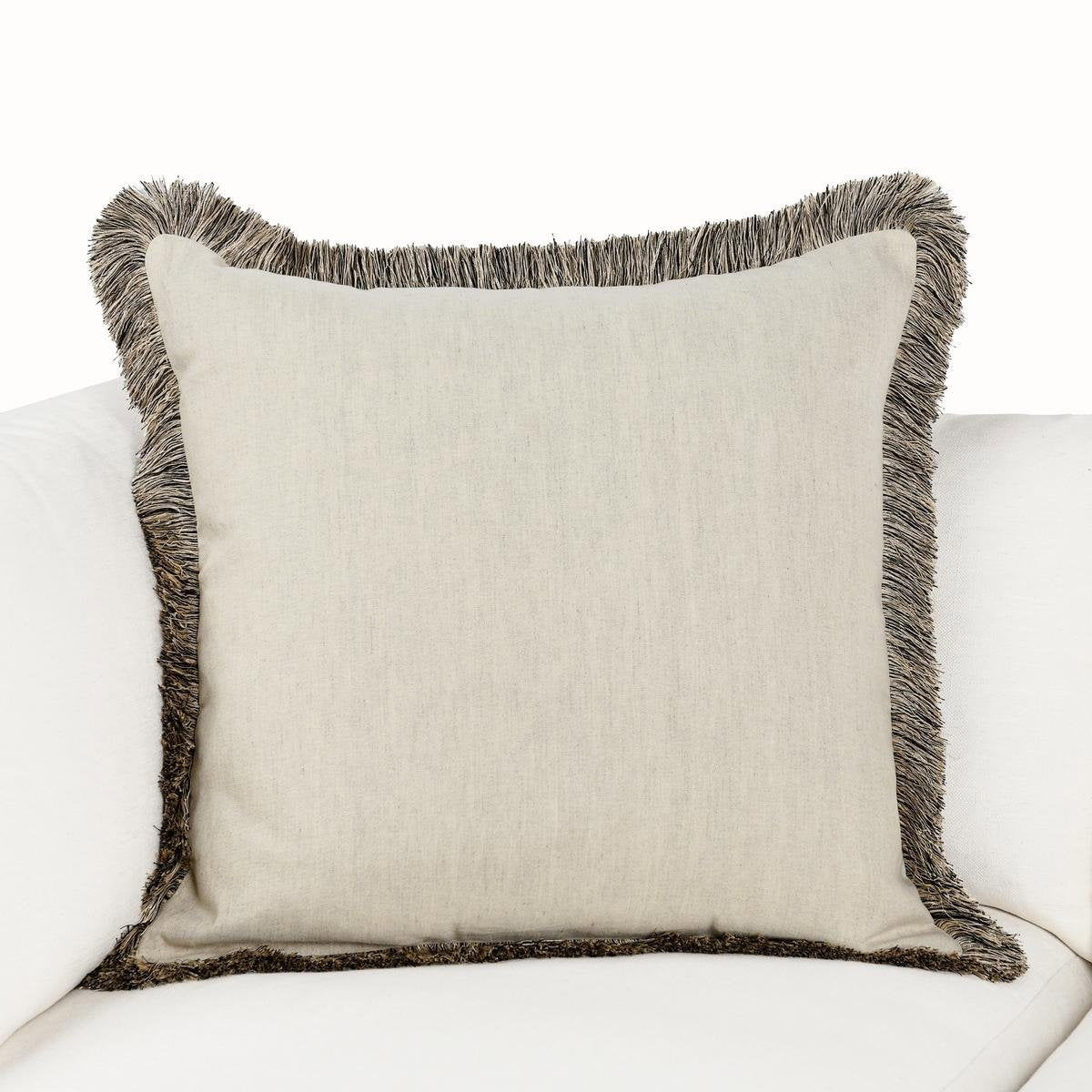 Natural linen square pillow with dark gray fringe, shown on a sofa