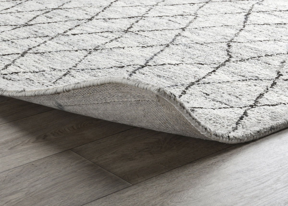 Corner of ivory and gray rug with textured edge and visible underside backing