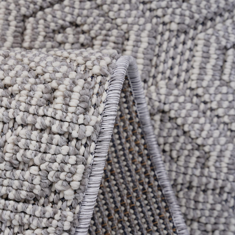 Geometric rug corner detail with braided fringe and textured dark gray pile